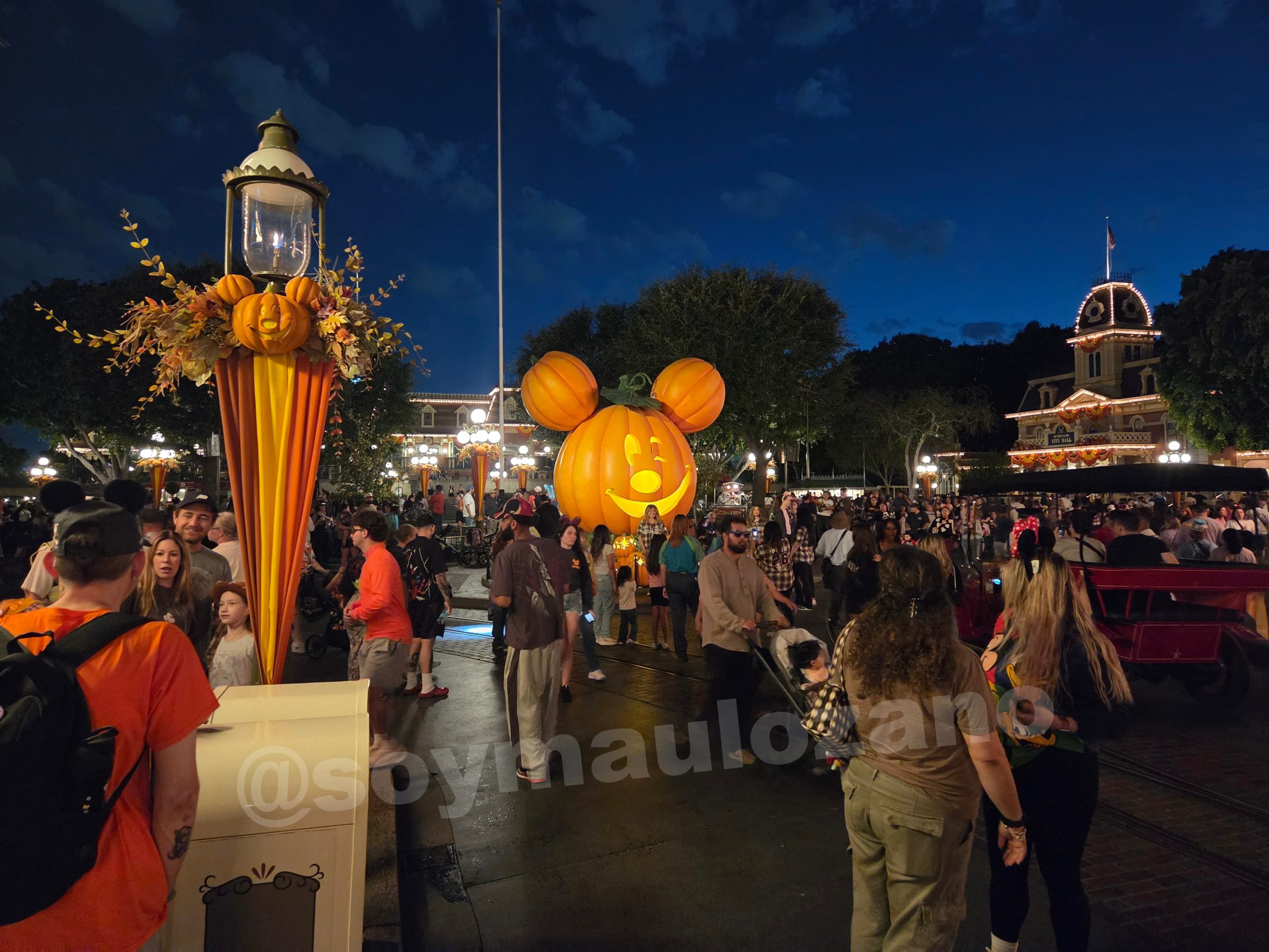 Calabaza iluminada y visitantes del parque de noche tomada con Galaxy Z Fold 8.