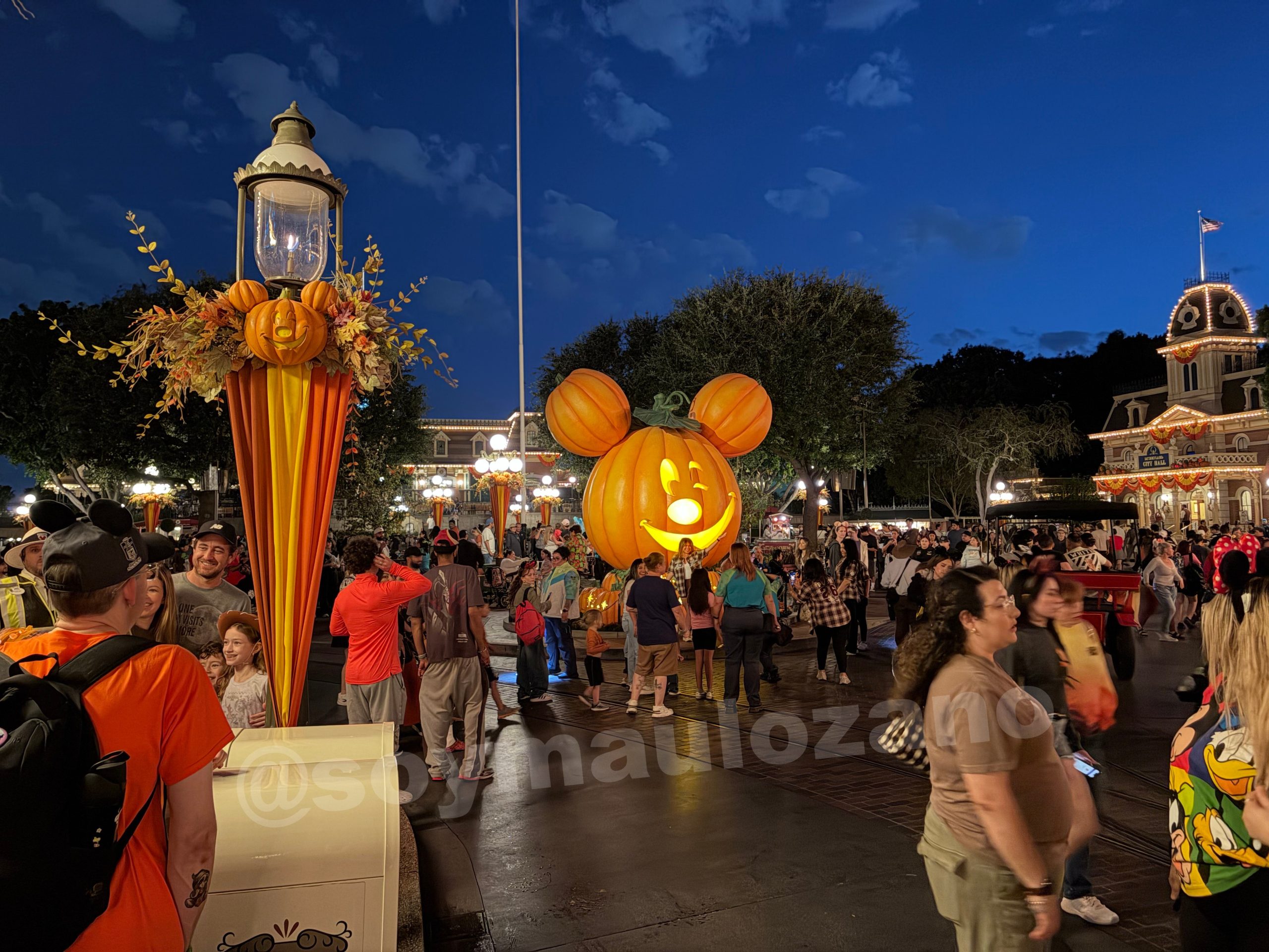 Calabaza iluminada y visitantes del parque de noche tomada con iPhone Duo.
