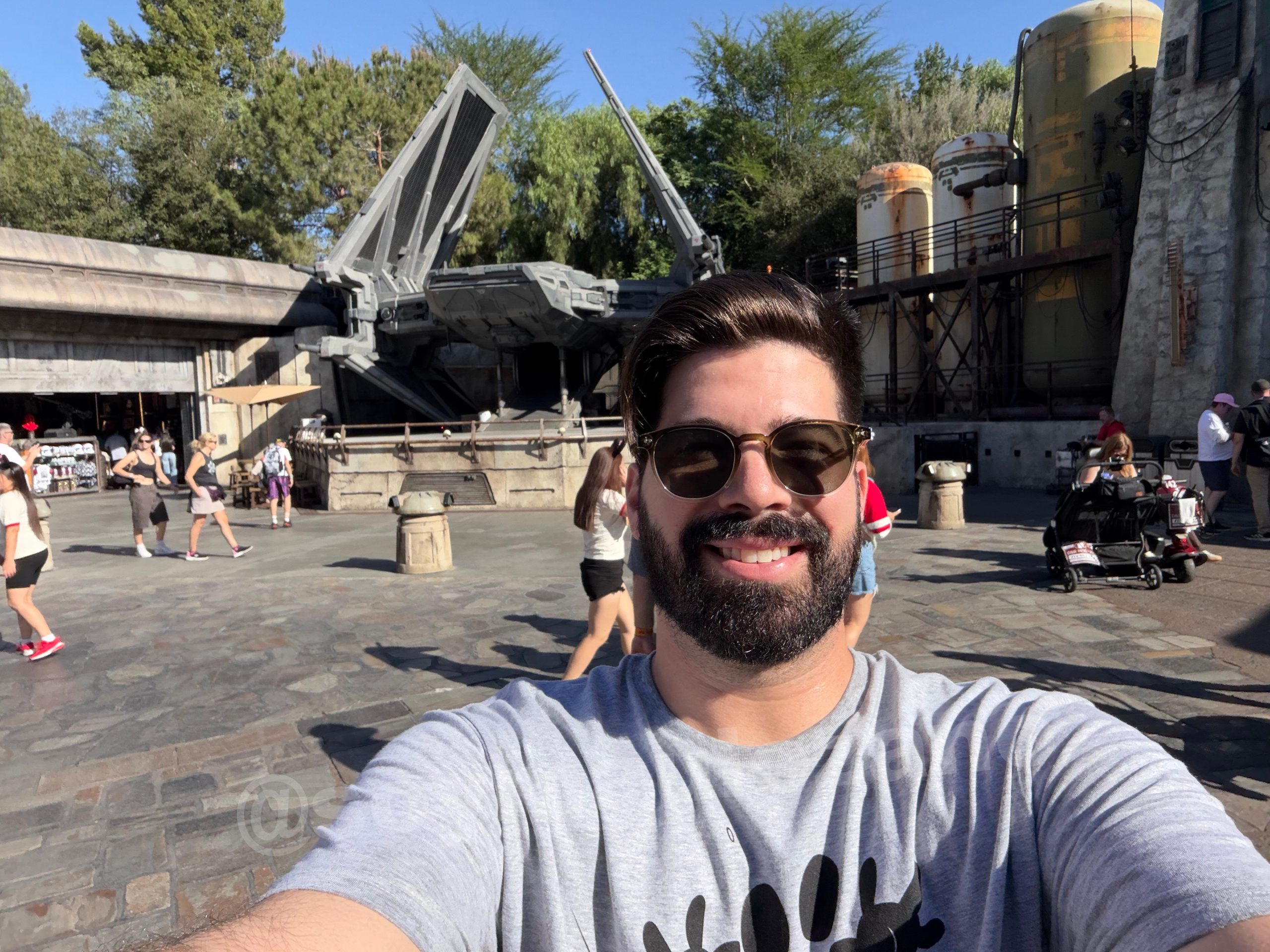 Selfie diurna de Mau con la nave y los árboles al fondo tomada con iPhone Duo.