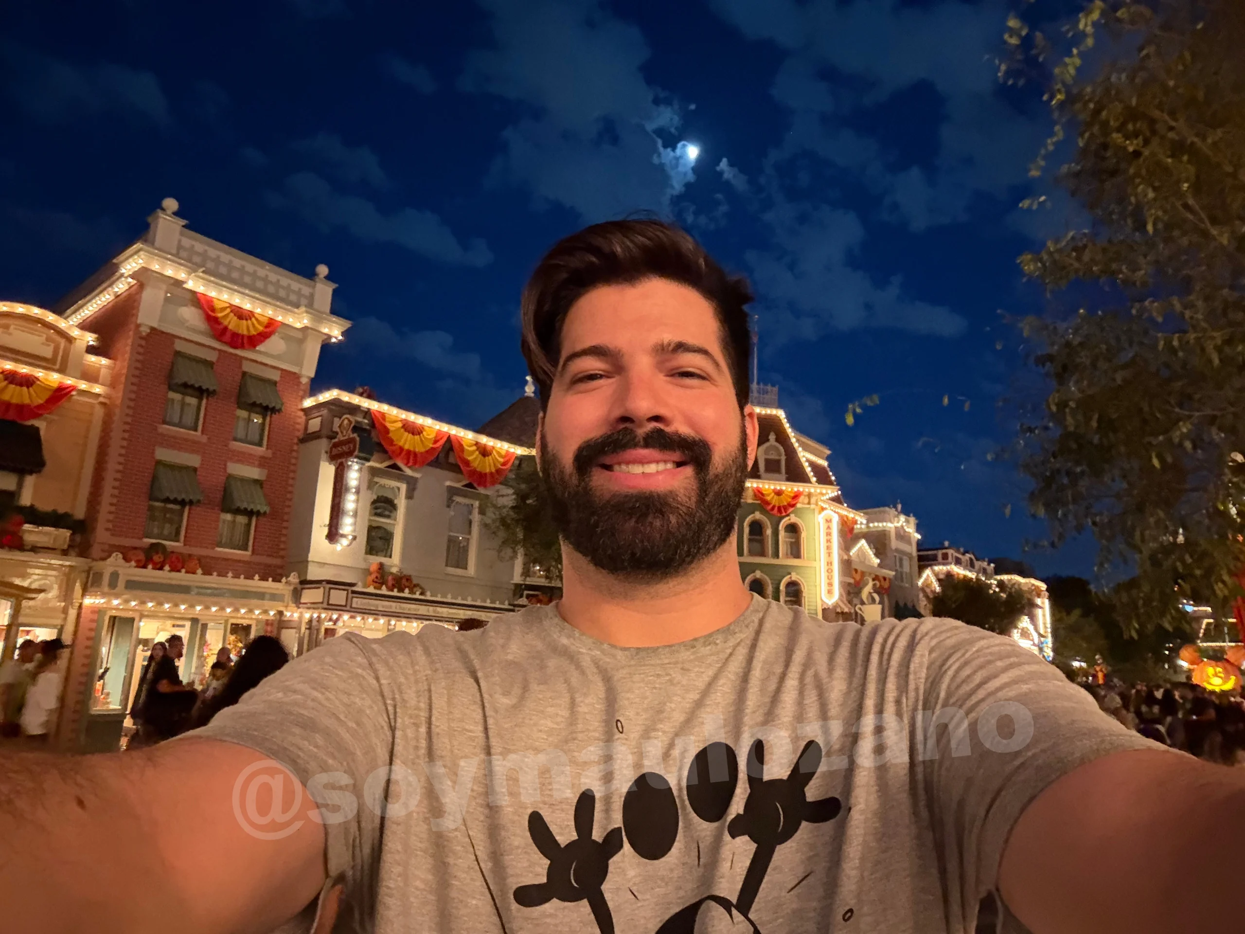 Selfie nocturna de Mau con luces del parque al fondo tomada con iPhone Duo.